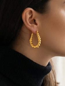 Close-up of golden U-shaped wave texture earrings on model wearing black sweater