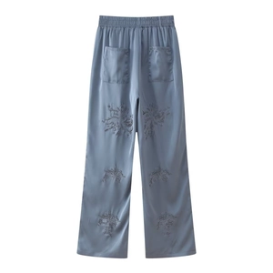Detailed view of blue satin wide-leg pants featuring intricate sequined floral embroidery