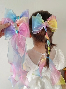 Detail of girls' rainbow gradient tulle bow hairpin with long ribbon tied in a braid
