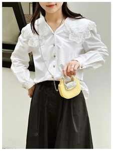 Close-up of a stylish yellow mini chain lipstick bag paired with a white lace shirt