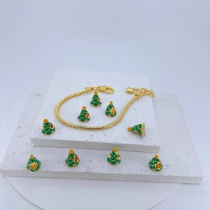 Detailed view of a gold snake chain bracelet with green enamel Christmas tree charms