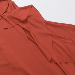 Detalle de la textura con volantes y costuras elegantes en este vestido rojo ladrillo