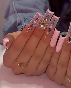 Detail of long square press-on nails with pink rhinestones and gold heart accents