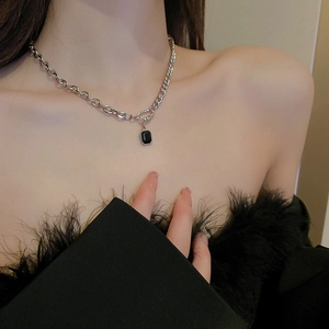 Detail of silver chain necklace with black rectangular pendant on a model's neck