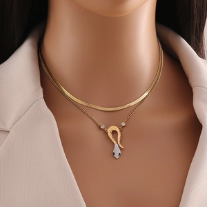 Detail of gold double-layer necklace featuring a sparkling diamond-encrusted snake pendant