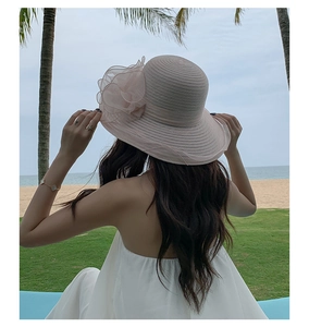 Detail of pink organza beach hat with floral decoration in a sunny outdoor setting