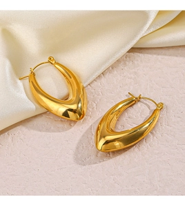 Dettaglio ravvicinato di orecchini a U cavi placcati oro 18K su elegante seta color crema