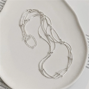 Detail of layered S925 sterling silver snake chain necklace with beads in a ceramic dish
