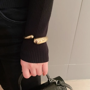 Detail of a minimalist gold teardrop open cuff bracelet with a polished mirror finish