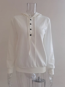 Detalle de sudadera con capucha de punto blanco con cuatro botones negros en el escote