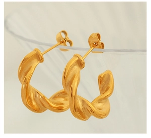 Detail of twisted gold C-shaped hoop earrings with elegant metallic texture and finish
