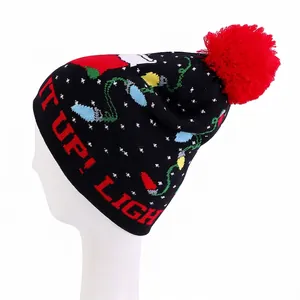 Close-up of knit Christmas beanie with red pompom and LIGHT IT UP text embroidery