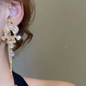 Detail of flower drop earrings with sparkling crystals and long metal tassels on model