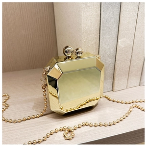 Close-up of golden octagonal acrylic clutch bag with a bead chain on wood surface