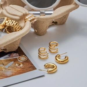 Detail of gold snake ear cuff with rhinestones and thick C-shaped stainless steel earrings