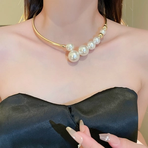 Gros plan d'un collier ras du cou doré géométrique avec perles blanches pour femme