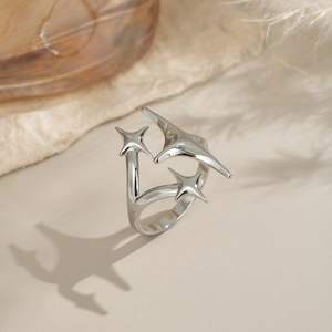 Close-up of polished silver star ring with deconstructed design on stone and feather background