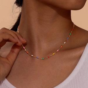 Close-up of golden stainless steel necklace with colorful beads on a model's neck