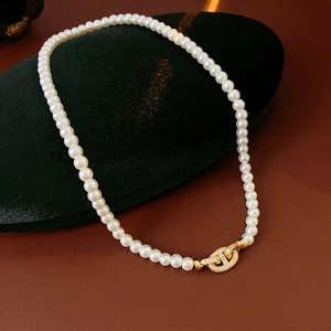 Detailed macro view of white pearl necklace with golden zircon clasp on velvet