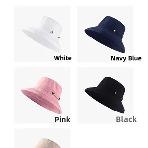 Détail de chapeaux de soleil en blanc, bleu marine, rose et noir avec boucles en métal