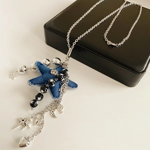Detail of titanium steel necklace with blue denim starfish pendant and silver charms