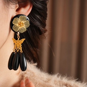 Detail of vintage beaded earrings featuring gold butterfly bows and black teardrop tassels