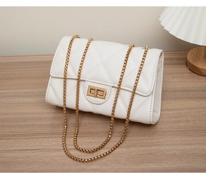 Detail of white quilted crossbody bag featuring a gold chain strap and twist lock