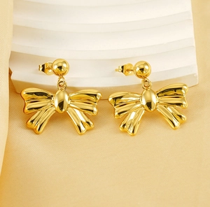 Macro shot of polished 18k gold plated stainless steel bow earrings on silk