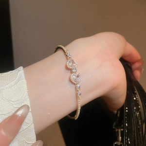 Detailed close-up of a gold heart-shaped zircon bracelet on a woman wrist with stones