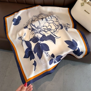 Detail of floral printed silk scarf with navy peony pattern and contrast rolled edges