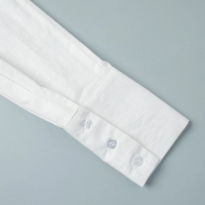 Detailed close-up of white shirt dress cuffs with three transparent buttons and linen texture