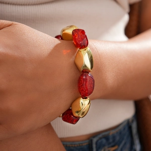 Close-up of bohemian beaded bracelet featuring irregular gold and red resin beads