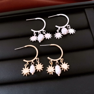 Detail of vintage sunburst pendants and baroque pearls on gold and silver hoop earrings