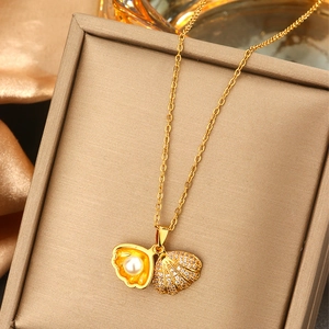 Macro shot of a golden shell pendant necklace with a white pearl and zircon accents