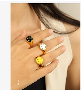 Close-up of 18K gold-plated smile face rings in black, white and yellow enamel detail