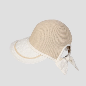 Close-up of straw sun hat featuring a beige woven texture and white ribbon bow detail