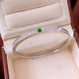 Macro detail of silver geometric bracelet with green gemstone in a jewelry box
