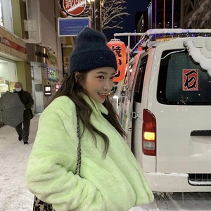 Women's warm fluorescent green faux fur coat and navy knit hat in snowy winter street