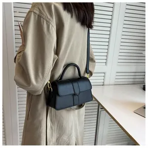 Sac à main moderne en cuir noir avec poignée et bandoulière porté par un mannequin