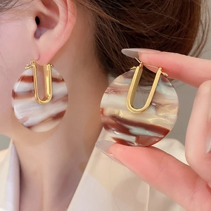 Gros plan de boucles d'oreilles en or en forme de U avec résine d'acétate marbrée