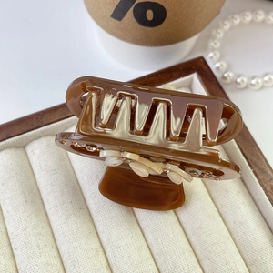 Close-up of brown acetate flower hair claw clip with rhinestones in a jewelry box