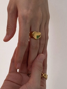 Macro detail of model wearing gold heart shaped and retro chain link metal rings