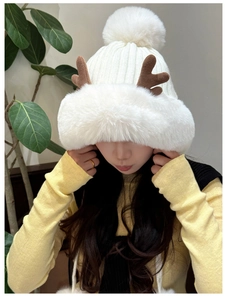 Close-up of winter knitted hat with plush antlers and large white pom-pom detail
