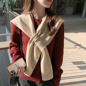 Knitted beige scarf wrap layered over a red cardigan for a cozy outdoor autumn look