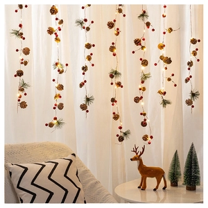 Detail of Christmas string lights with red berries, pine cones and warm LED glow