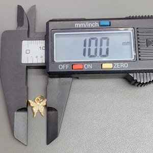 Macro shot of a 10mm golden butterfly pendant with clear zircons measured by digital caliper