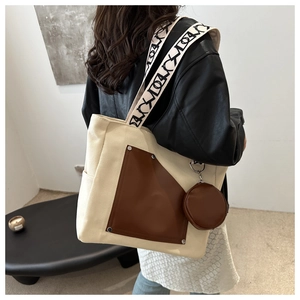 Detail of canvas tote bag with brown leather pocket and a round mini pouch accessory