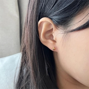 Close-up of minimalist golden star stud earring worn on ear with high-quality metal finish