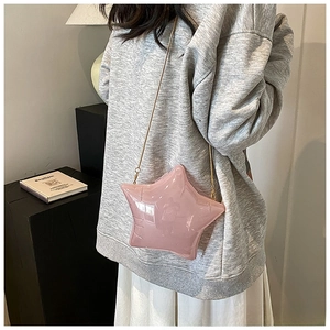 Pink star-shaped acrylic crossbody bag with gold chain strap on shoulder
