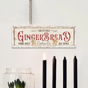 Macro detail of vintage North Pole Gingerbread wooden sign on a minimalist white wall